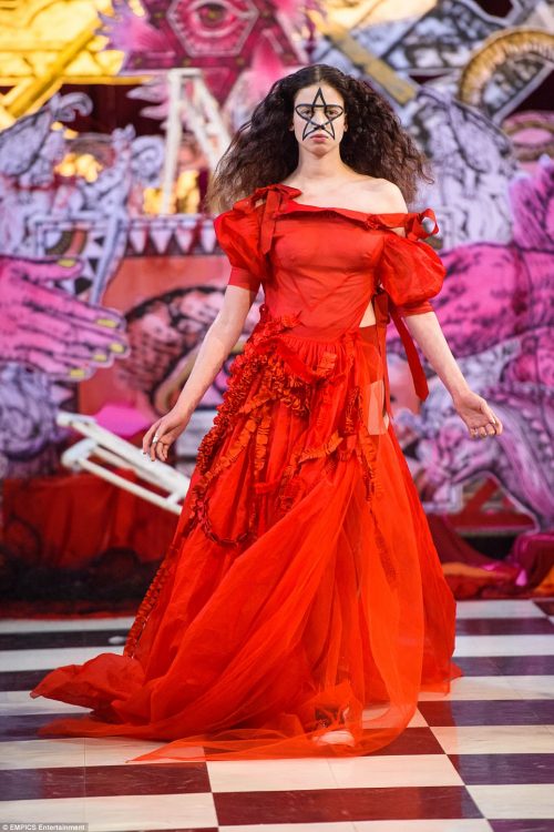 Эта модель носит ритуальное красное платье с большой пентаграммой, нар